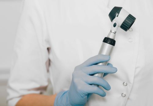 Dermatologist holding a dermoscope ready to check a patients recurring skin cancer